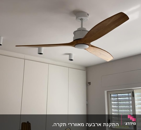 מאוורר תקרה עם כנפיים מעץ מותקן על תקרה לבנה